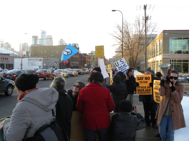 many people holding up yellow signs on the sidewalk