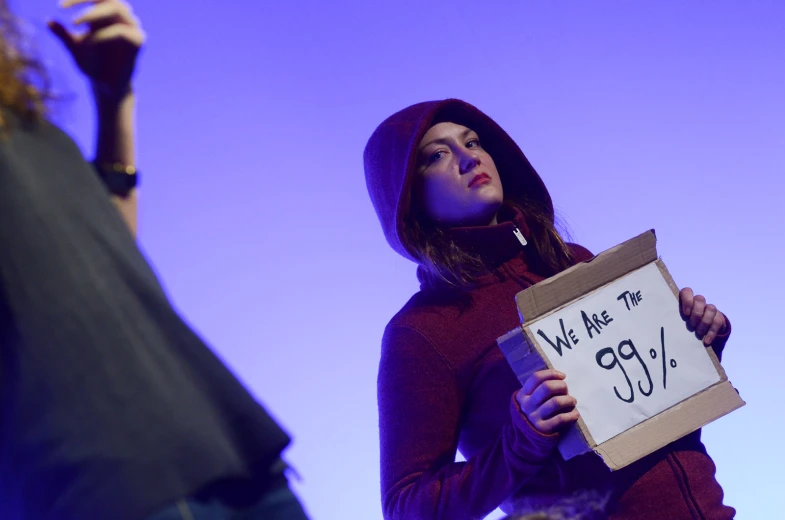 the woman in the red jacket is holding a sign