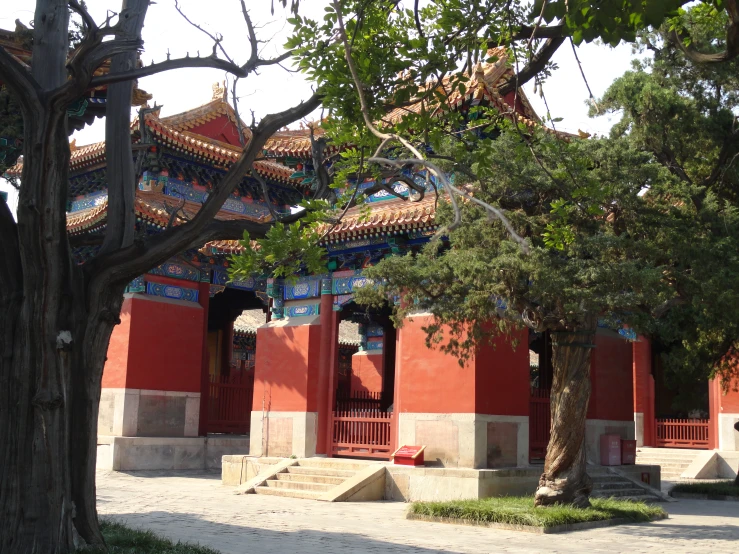 an old red building with a staircase to it and two trees