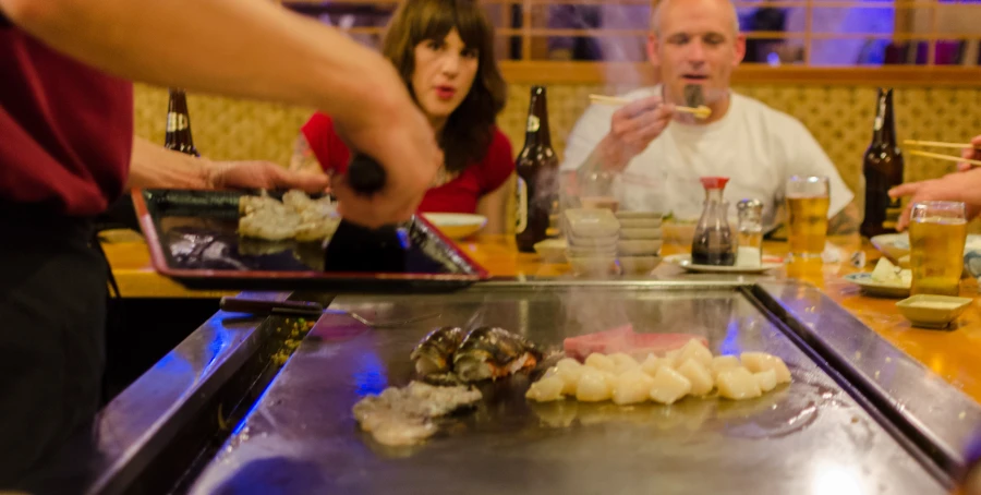 the people are enjoying sushi and chopsticks