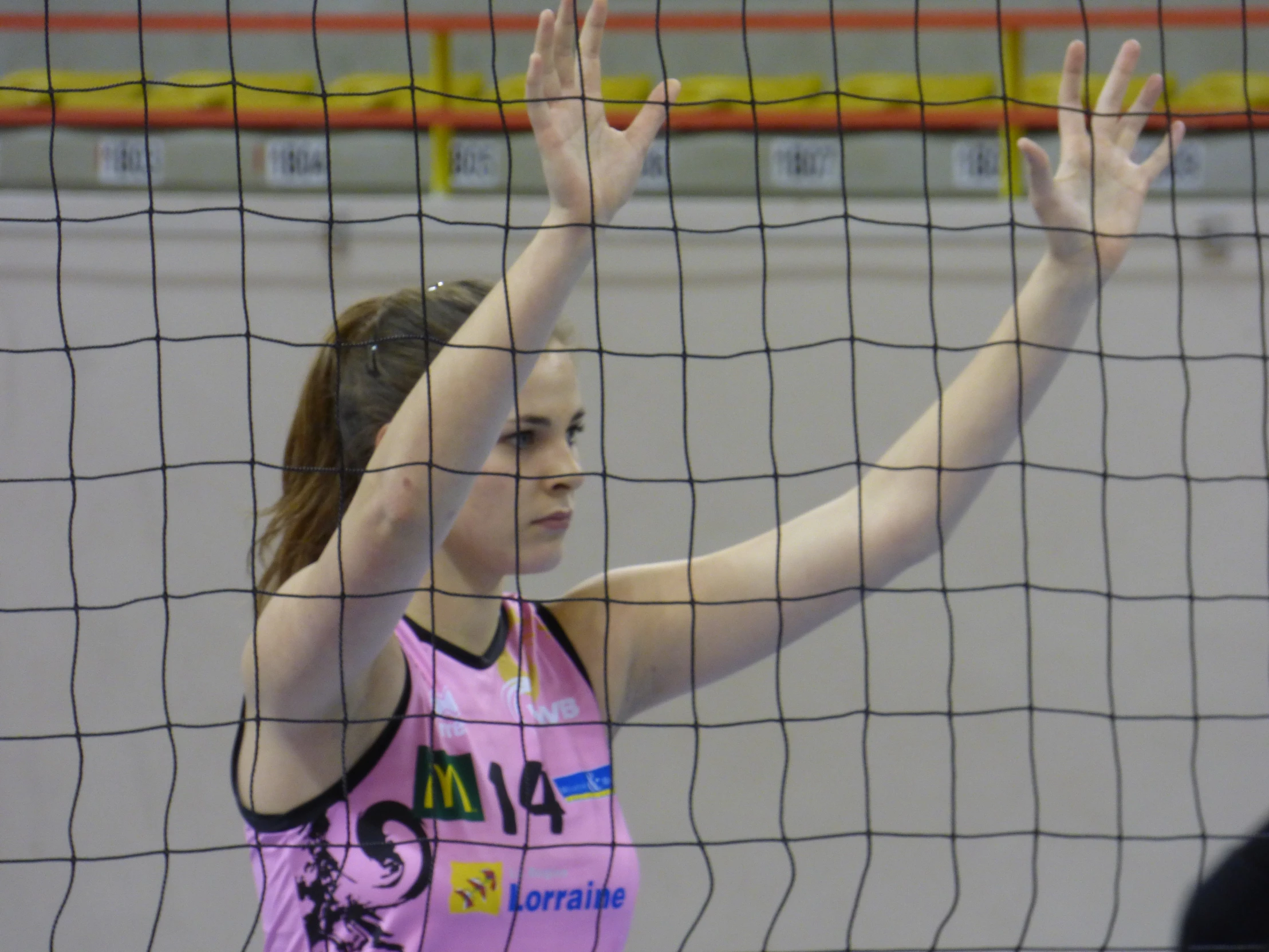 a woman standing in front of a volleyball net with her hands on her head