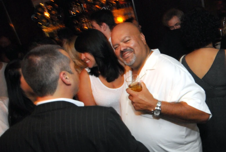 a smiling man in white is standing at an event