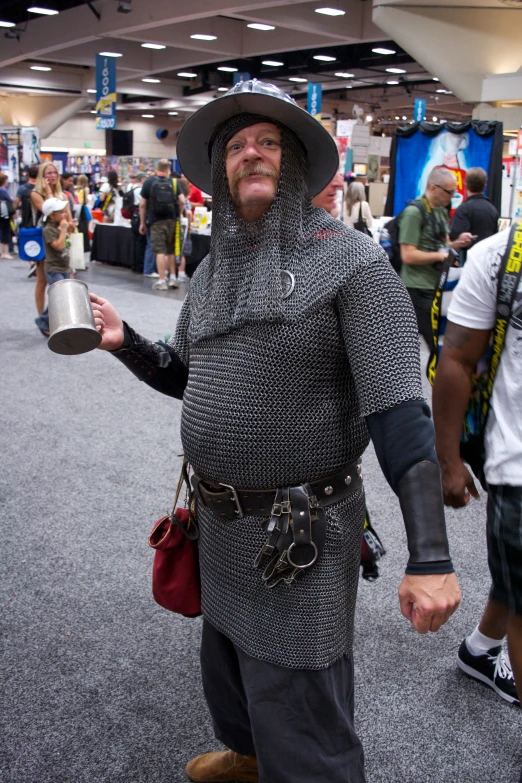 a man in medieval costume, carrying a tin cup