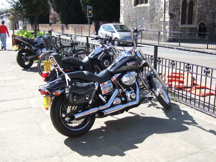the motorcycle is parked in front of a fence and curb