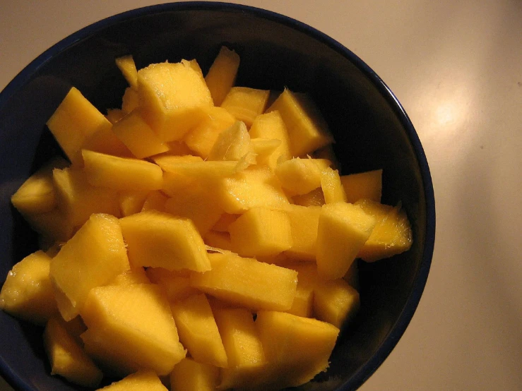 the cut up pineapples are in a blue bowl