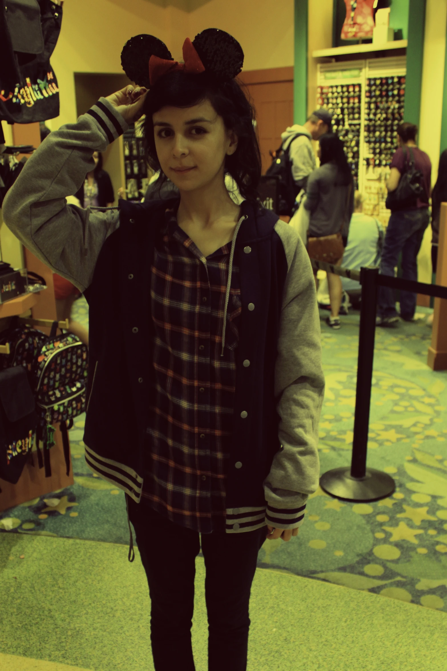 a girl in a mickey ears hat stands in a store