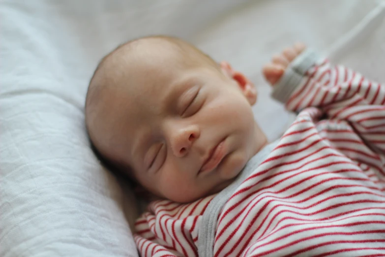 a baby lays down on a bed, sleeping