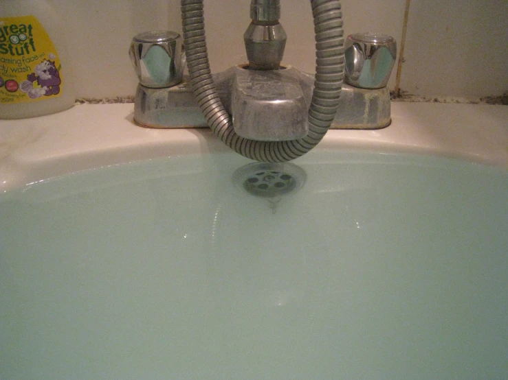 a green sink with a chrome faucet running from the water