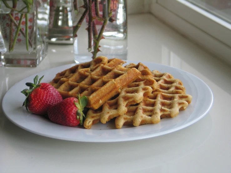 a plate of waffles with strawberries next to it