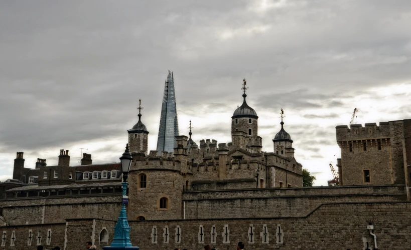 a stone castle wall with two towers, and a spire in the distance