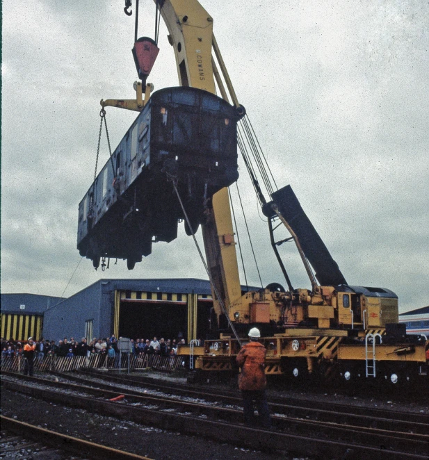 a train is lifting an object onto a rail car