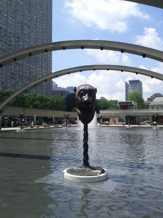 a sculpture with a face stands in a pool