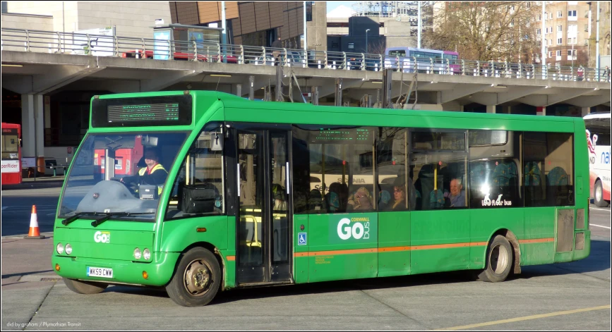 the large green bus is traveling down the street