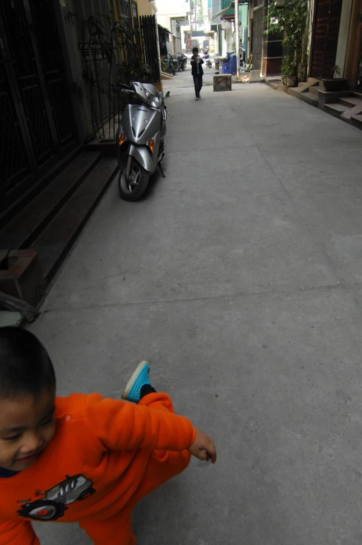 a child playing with a toy skateboard down a street