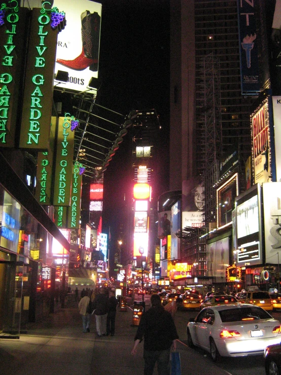 people are walking on the sidewalk in the city at night