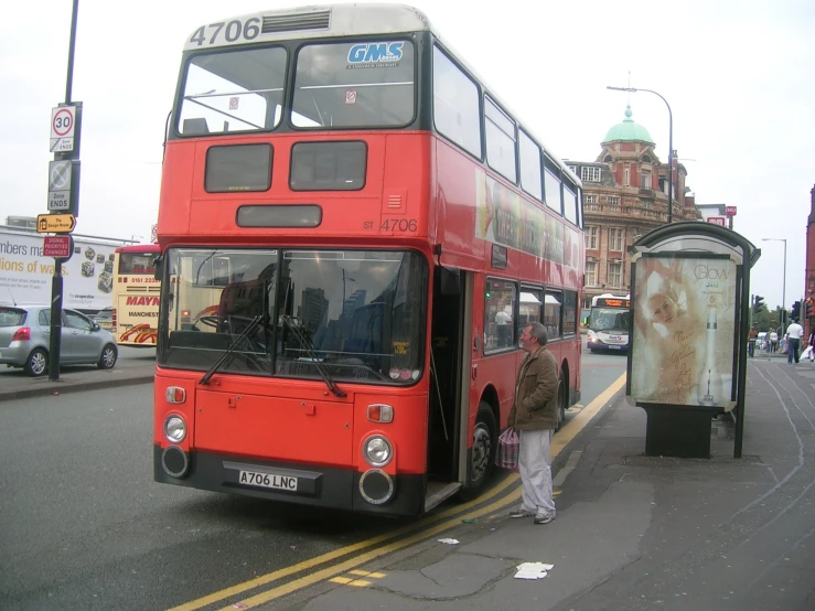 a large red bus is standing by a curb