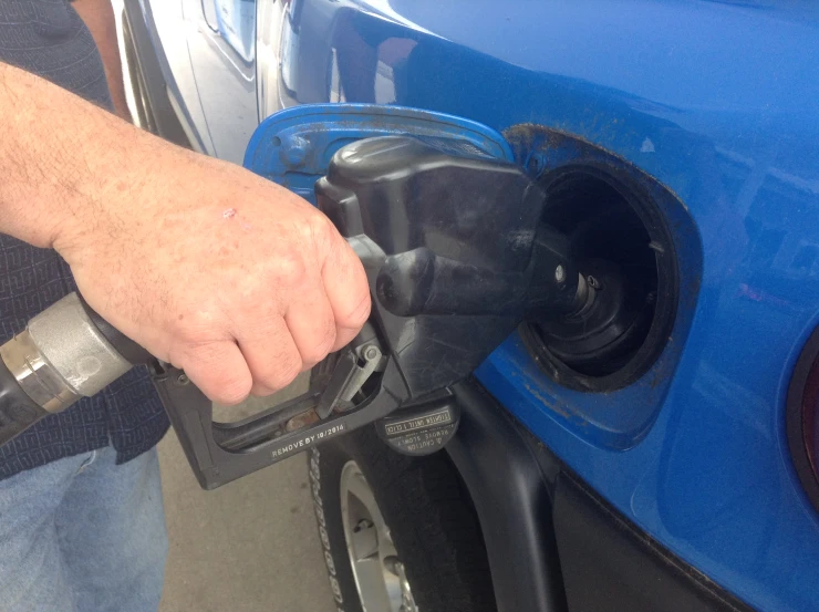 person pumping gas into vehicle at the station