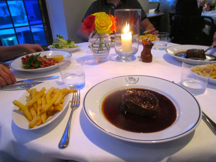 a dinner table set with plates of food and a candle