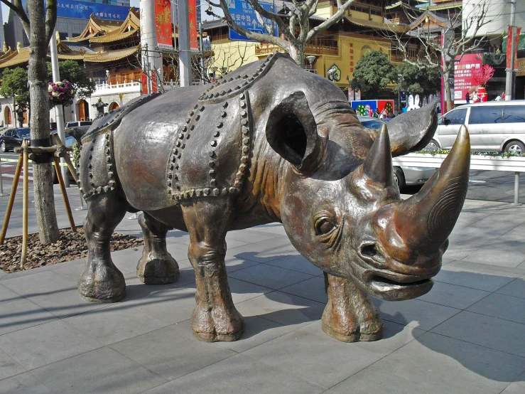 a statue of a rhino and an animal sculpture on the side of a road