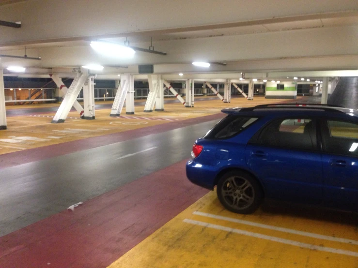 blue car parked in parking garage with yellow line