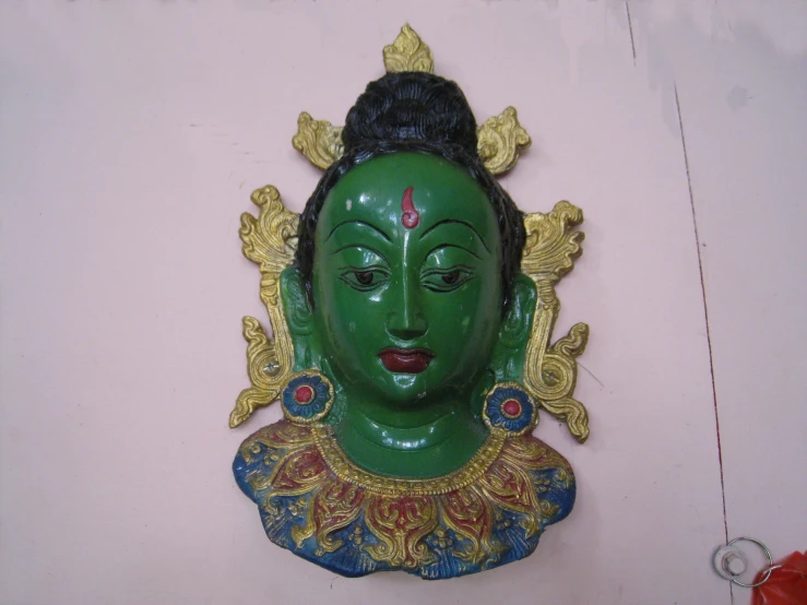 the green face of a statue is painted in gold