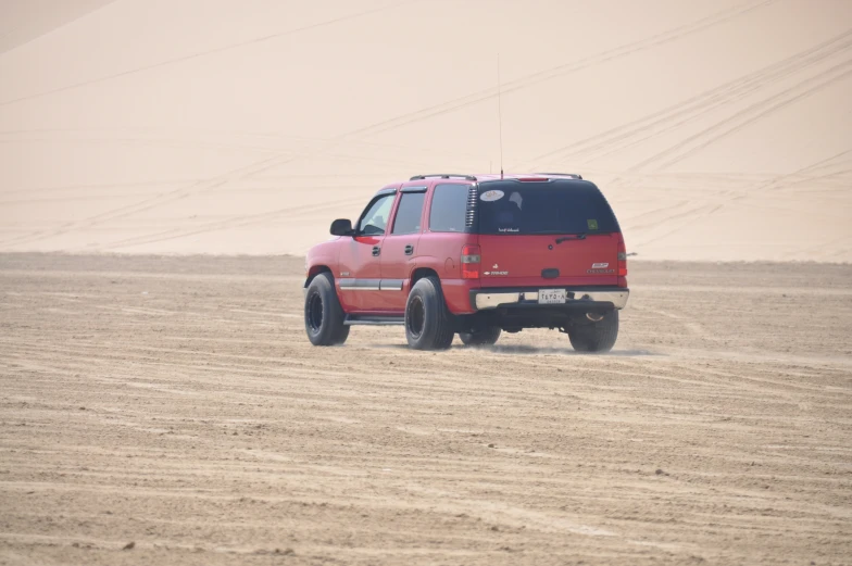 the red vehicle is driving through the desert