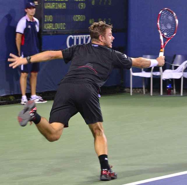 a man in black shirt and shorts playing tennis