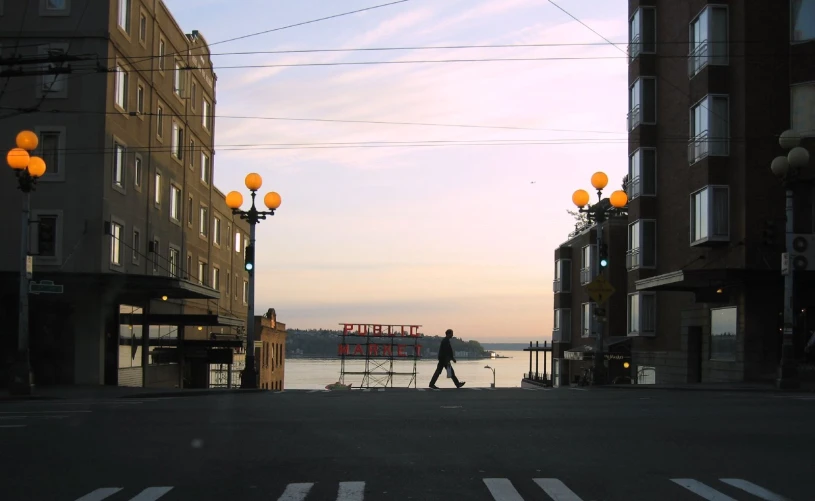 person walking through an intersection of buildings overlooking water