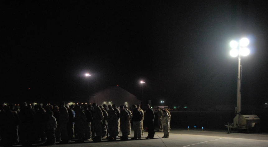 a long line of men in military clothes standing in the dark