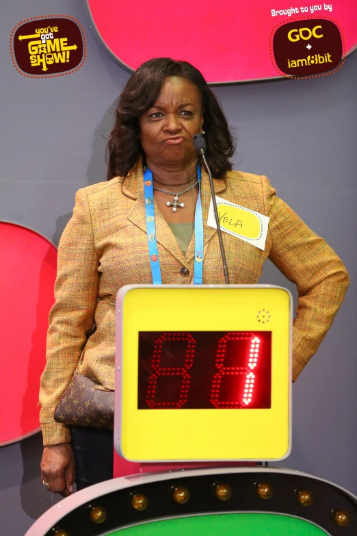 a woman standing at a podium holding an electronic clock