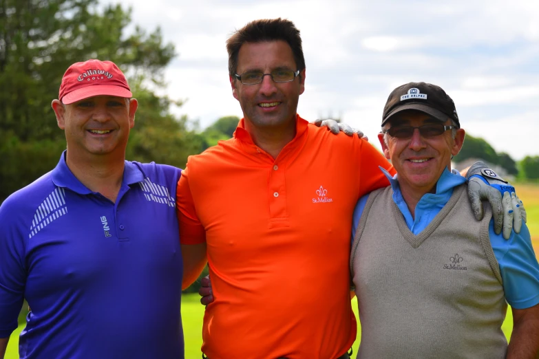 three men stand together in front of a golf course