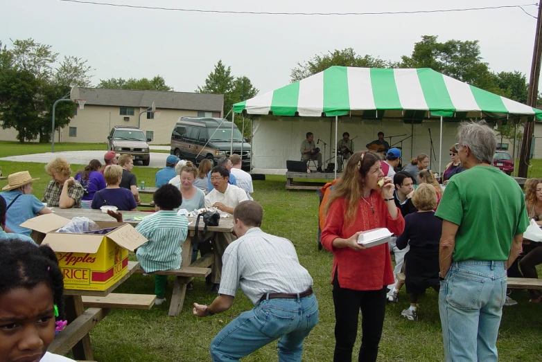 many people gather at a picnic while there are a lot of tents