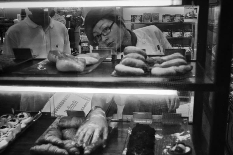 a man working at a bakery counter with pastries