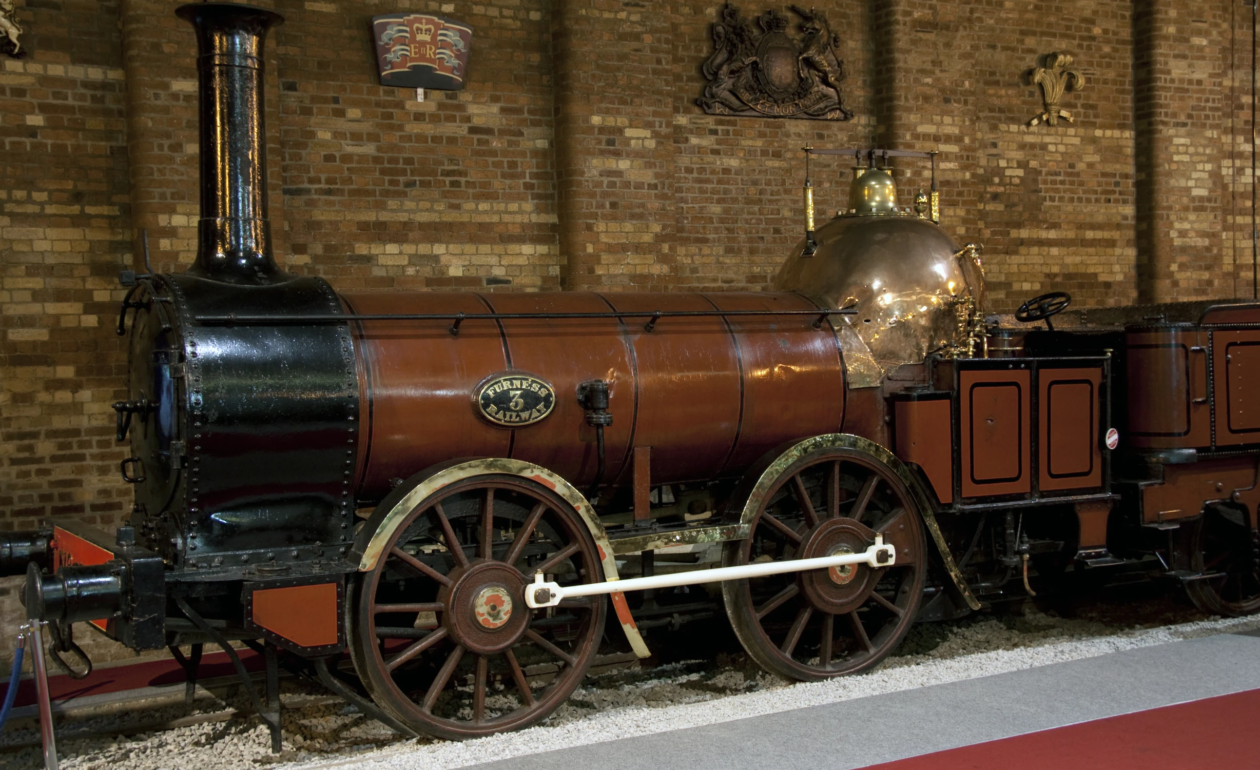 an old fashioned steam engine is parked near the brick walls