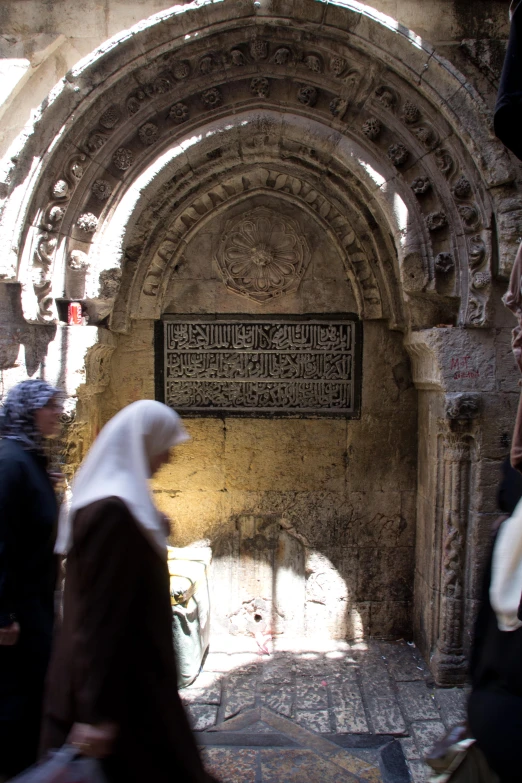 several people are walking through an old, stone building