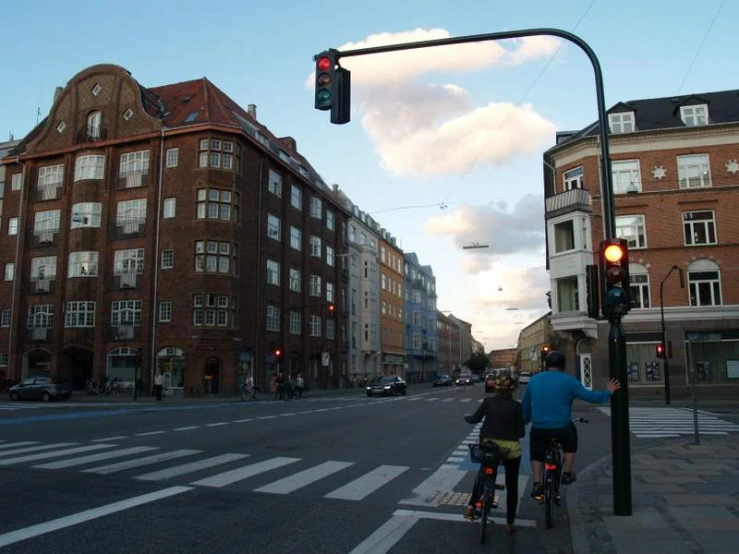 two people riding bicycles under a traffic light