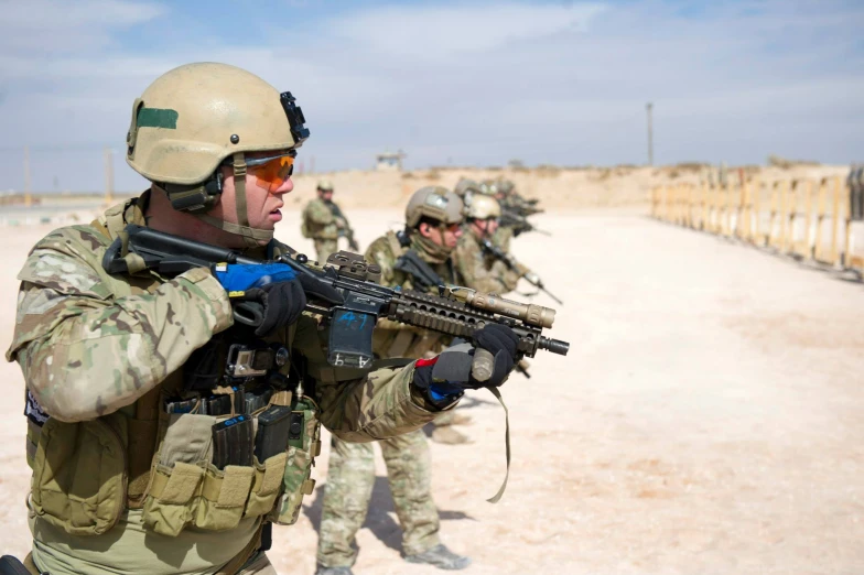 military men in camouflage gear with rifles in desert