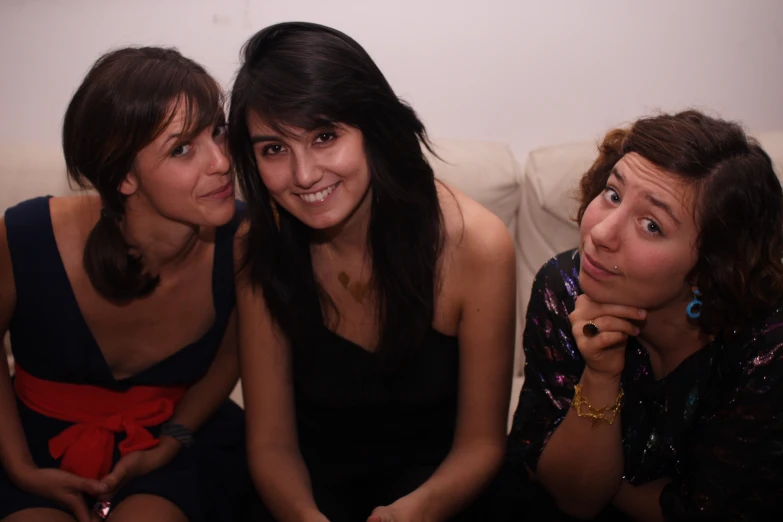 two ladies are sitting on a white couch and one is looking up