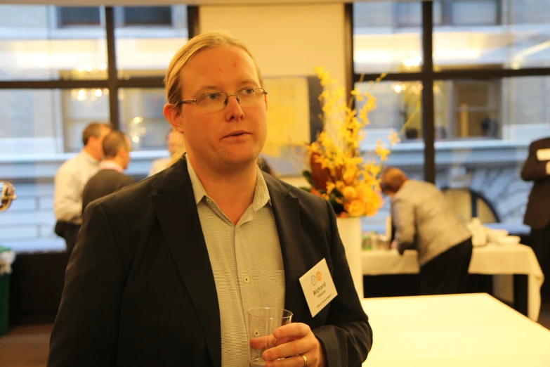 a man with glasses holding a wine glass in front of a table