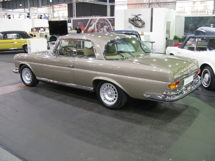 a tan car with a white roof and silver wheels