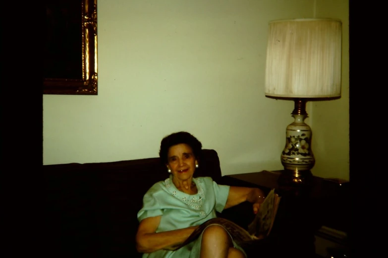 a woman sitting on the couch in front of a lamp