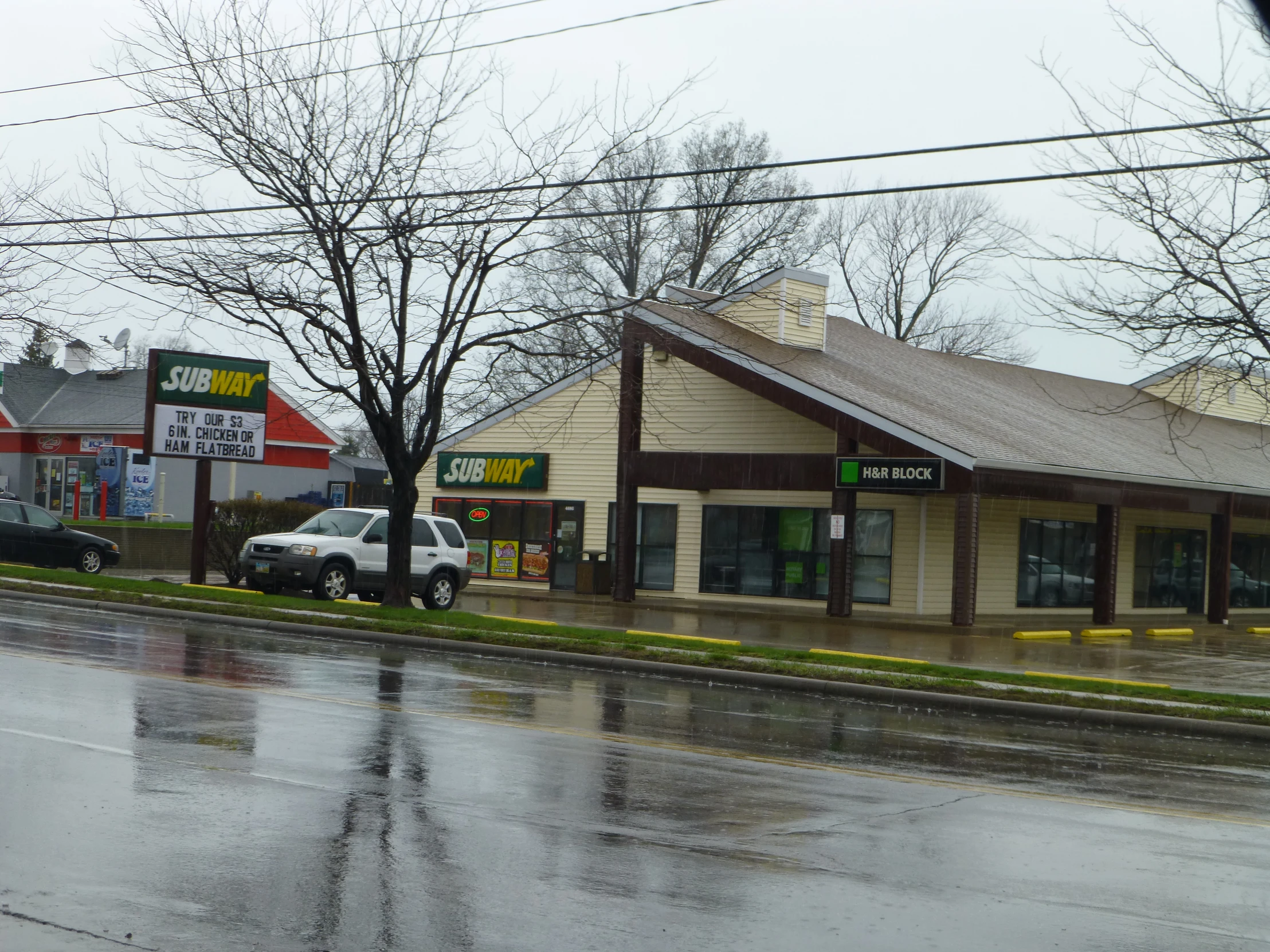 the small store has cars parked outside and on the side walk