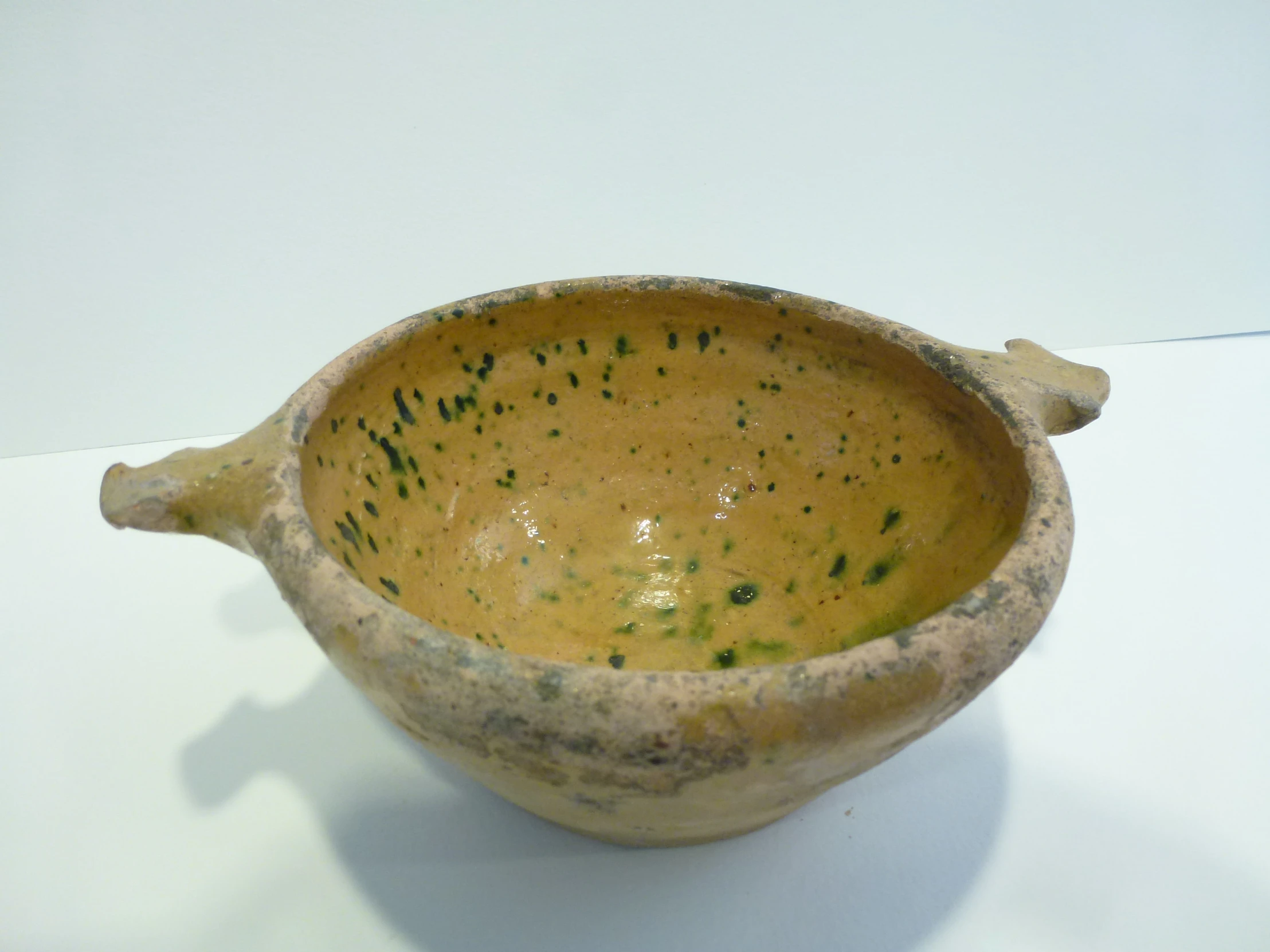 a brown clay bowl sitting on top of a white counter