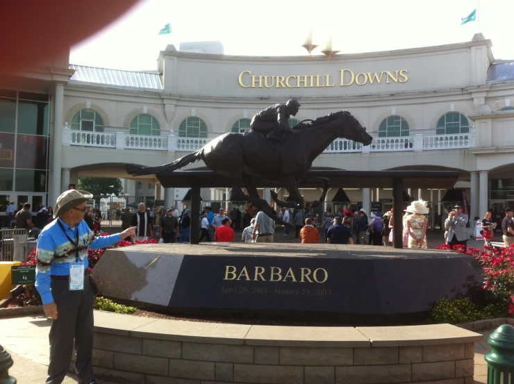 people looking at the statue of a jockey and horse