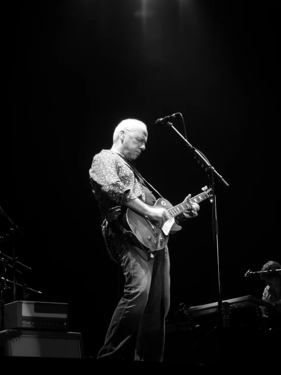 a person standing on stage with a guitar and microphone