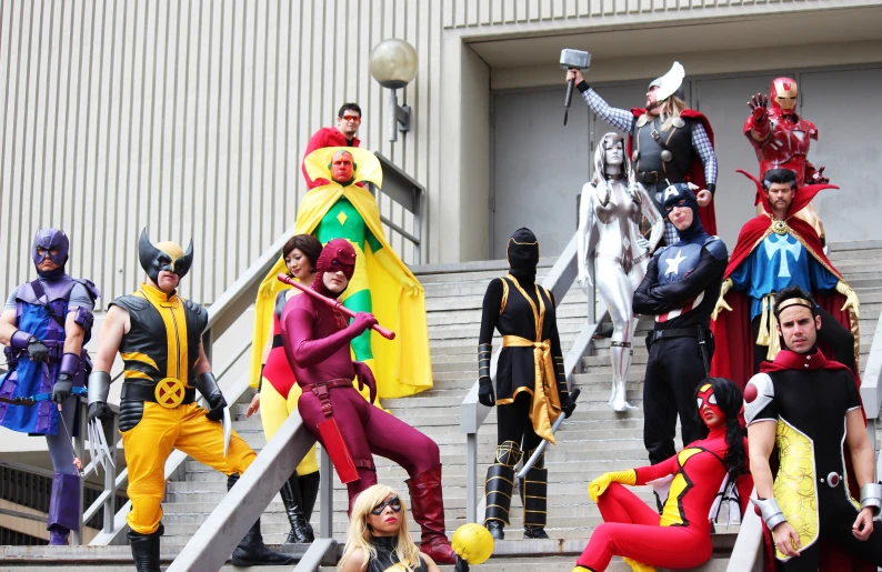 a bunch of people dressed as various comic characters posing on some stairs
