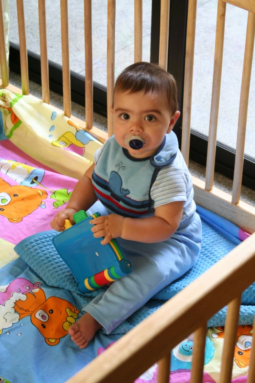 a baby in his crib eating a toy