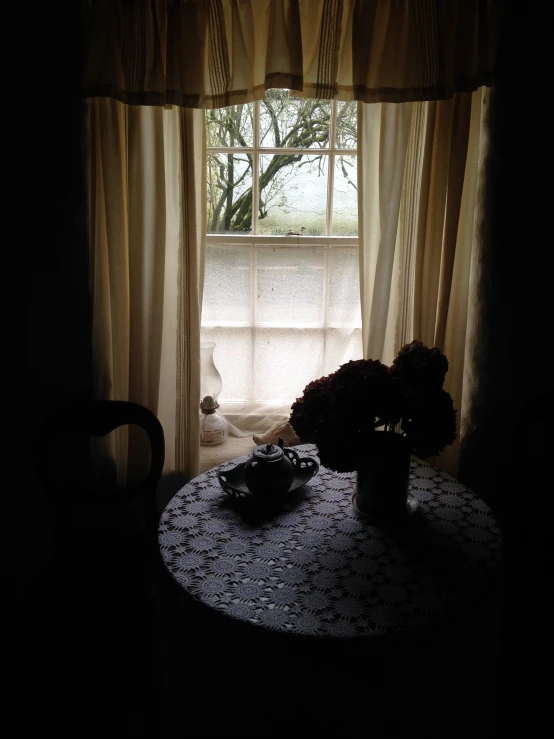 table and chair near window with a lace cloth