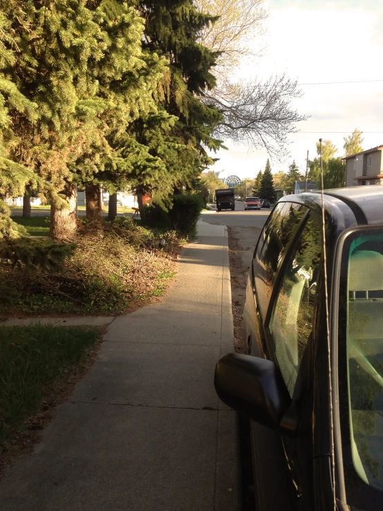 a car parked in front of a tree lined sidewalk