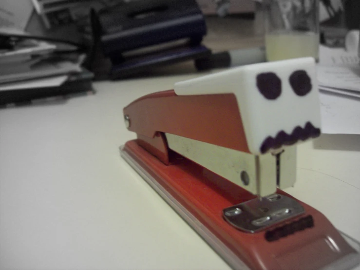 a strange stapler with a creepy face sticking out of it